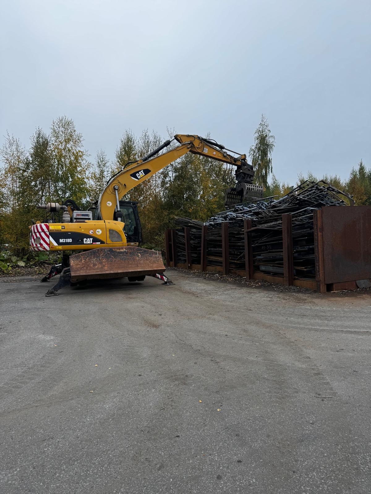 CAT M318D -materiaalinkäsittelykone lajittelukouralla romupihalla