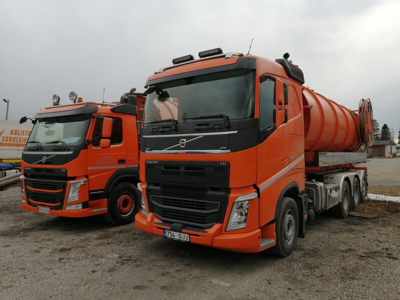 Kaksi oranssia Volvo-imuautoa pihalla